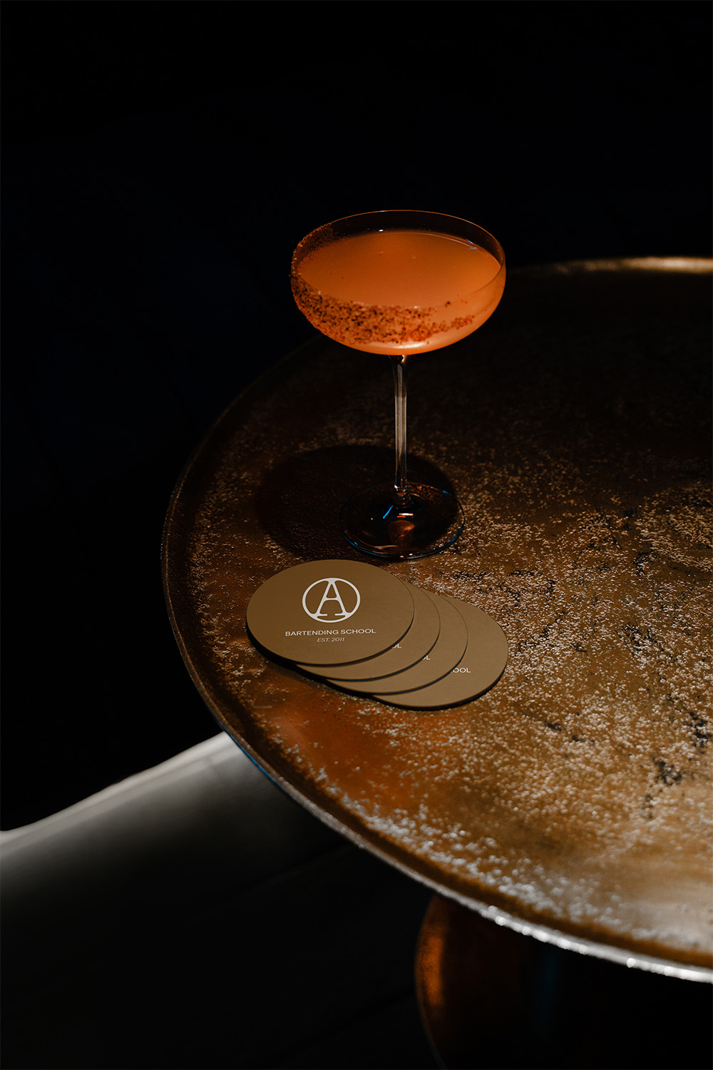Untersetzer mit dem Logo der Alchemy Bartending School – Branding-Maßnahmen von Indigo Estudio